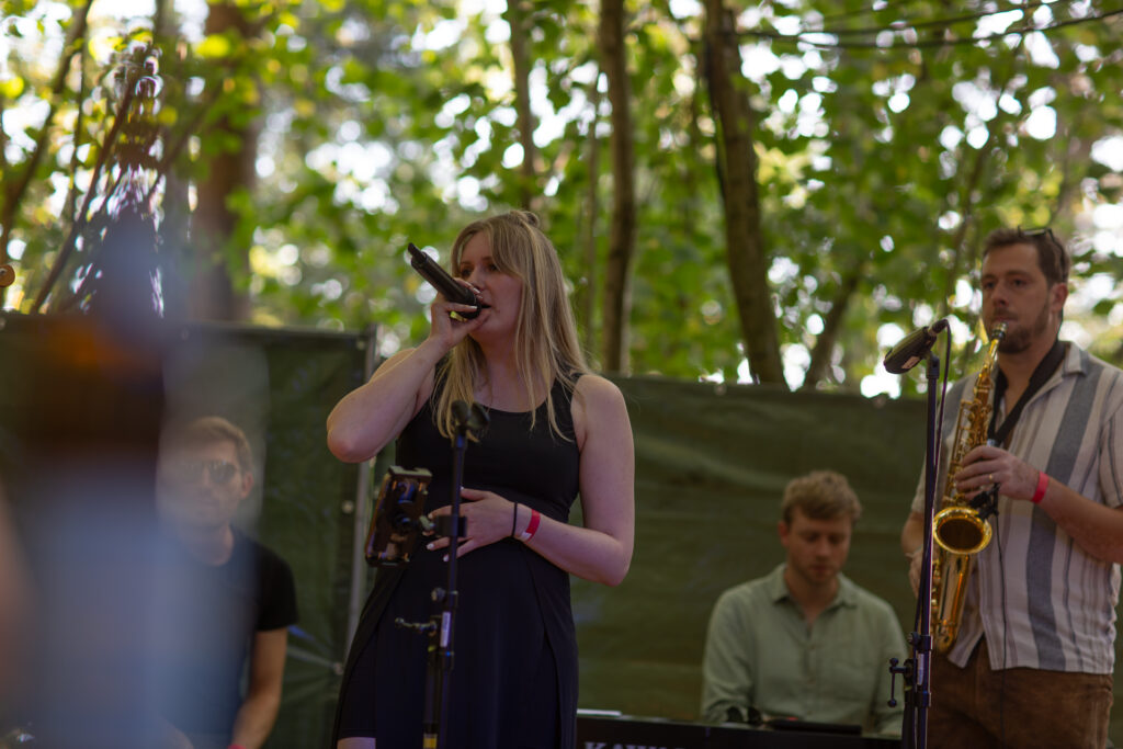 Sarah am Mikrofon, Basti am Saxophon, auf einer Waldbühne